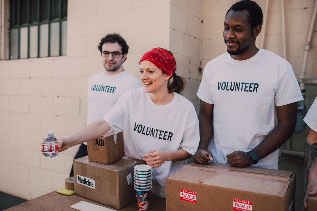Photo by RODNAE Productions Three volunteers handing out supplies.