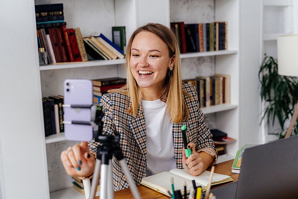 A professionally dressed girl using a tripod to videoconference
