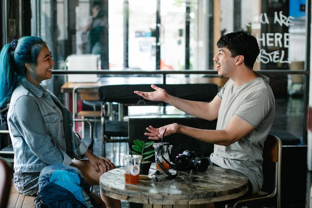 Photo by George Pak on Pexels A man and woman sitting at a table laugh and talk.