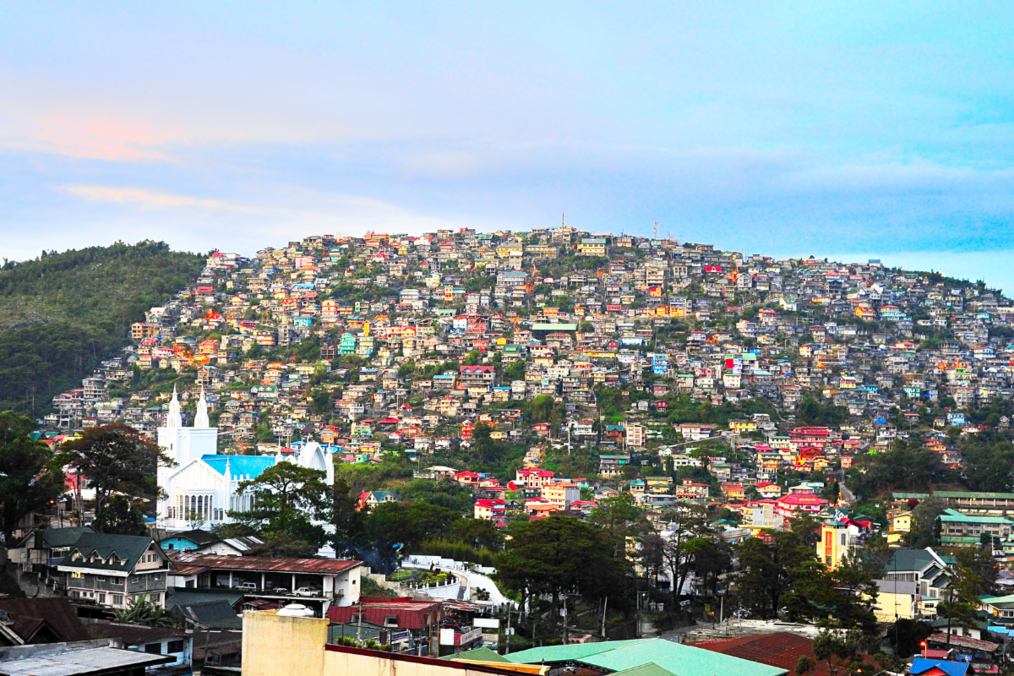 A hillside of colorful homes in The Philippines with a blue and pink sunset in the background