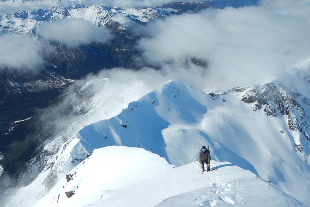 A climber summiting a snowy mountain