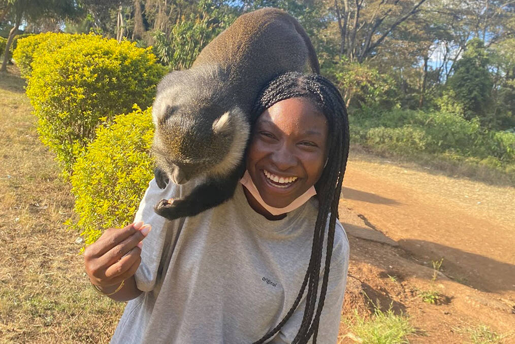 A young volunteer with an animal on her shoulder being fed
