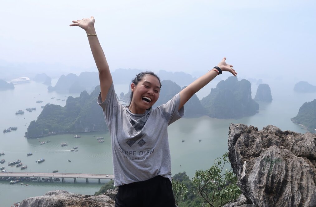 A young person standing in excitement in front of a body of water