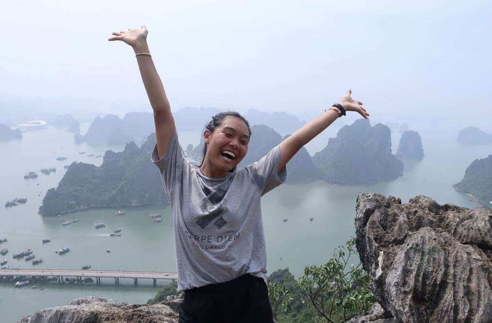 A young person standing in excitement in front of a body of water