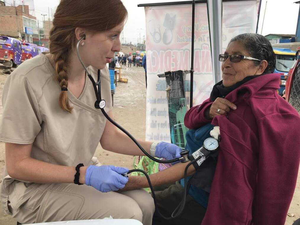 A volunteer taking the blood pressure of a patient