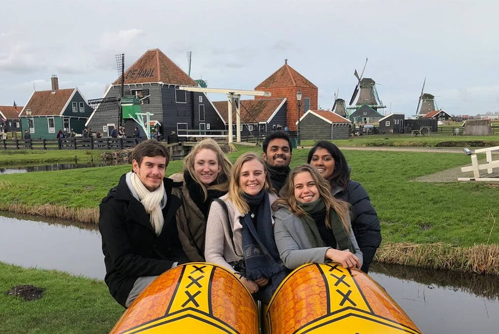 A group of 6 students standing in front of windmills