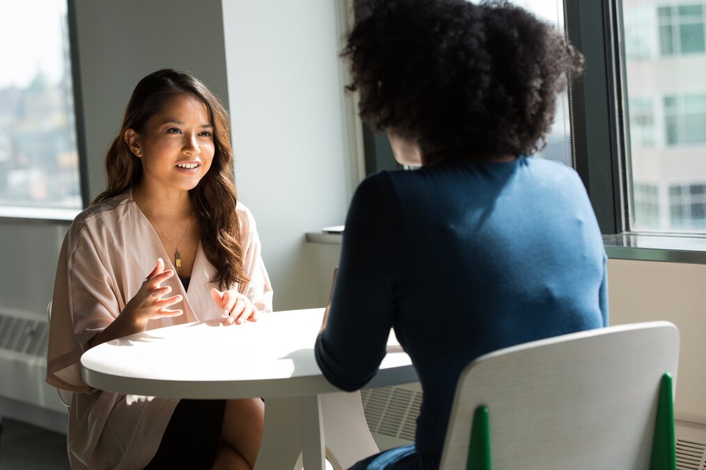 Photo by Christina @ wocintechchat.com on Unsplash Two women sitting at a table talking.