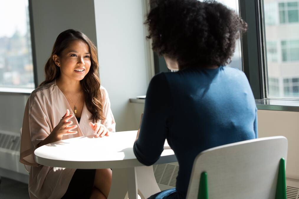 Two women sitting at a table talking.