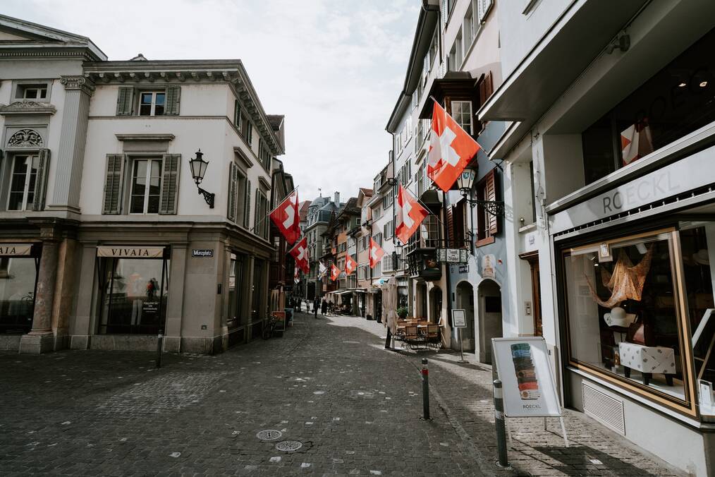 A street in Switzerland with Swiss flags hanging from shop fronts.