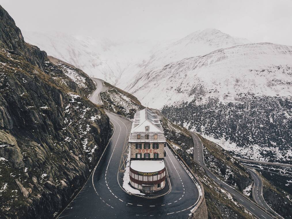 A snowy mountain side with winding roads around a skinny building with the label "hotel"