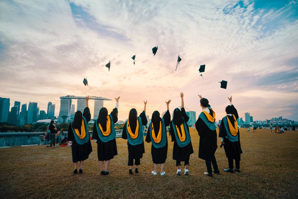 A group of students throw their graduation caps into the air.