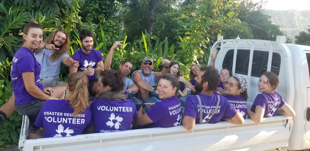 Dan, All Hands and Hearts Dominica A group of volunteers sit in the bed of a truck and smile for the camera.