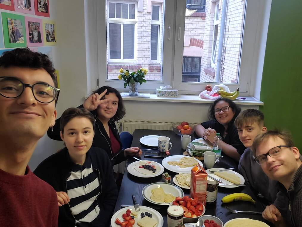 Several people sit and smile at a table with breakfast food on it.