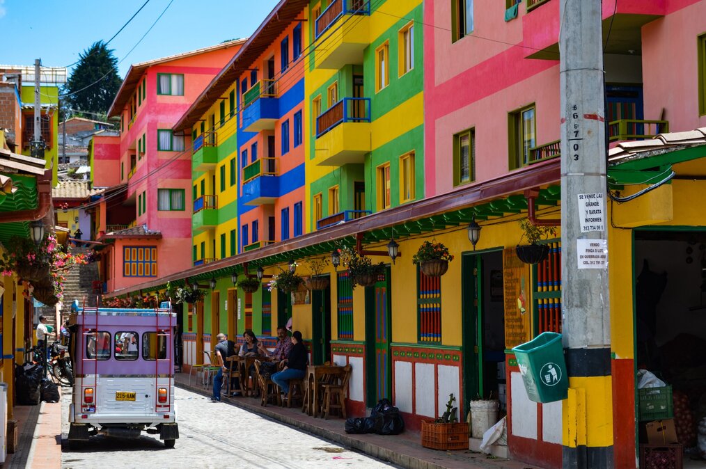 Photo by Saul Mercado on Unsplash Pink, green, yellow, and blue painted houses on a street in Colombia.