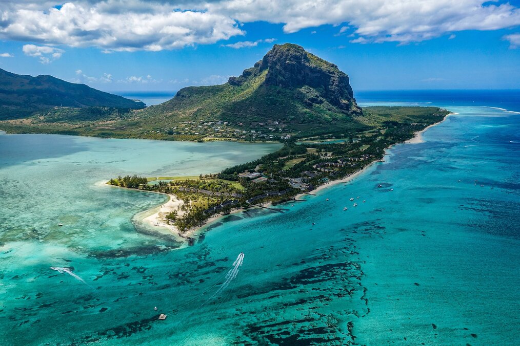 Photo by Xavier Coiffic on Unsplash A mountain on an island surrounded by clear blue water in Mauritius.