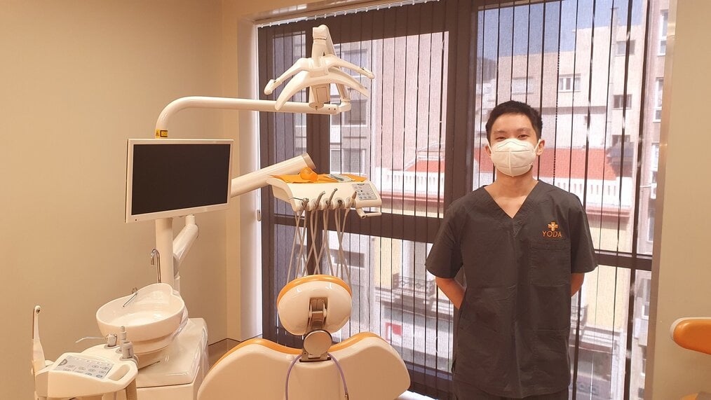 Dentist standing next to patient chair and dental equipment