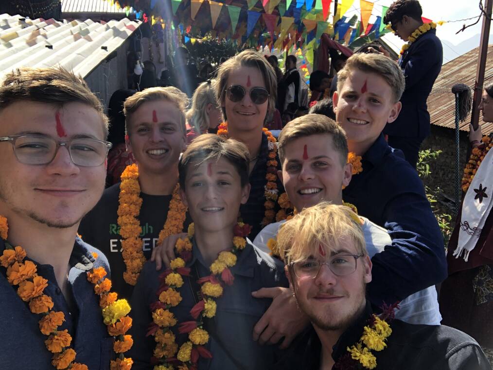 A group of volunteers wear flower necklaces and pose for the photo.
