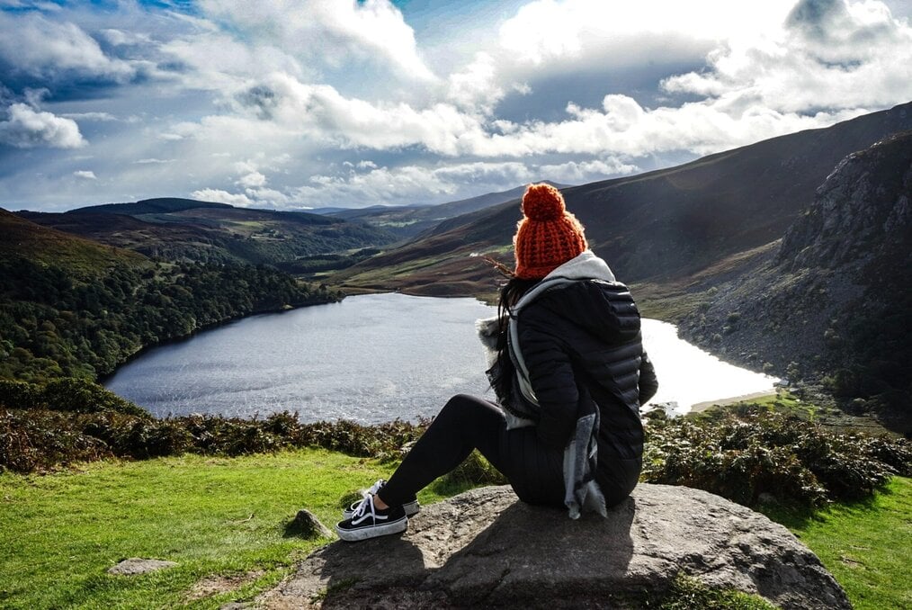 Image curtesy of Jake Stahl, Unsplash A girl with a red beanie looks out over a lake in New Zealand