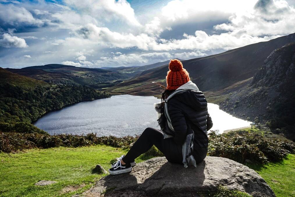 A girl with a red beanie looks out over a lake in New Zealand