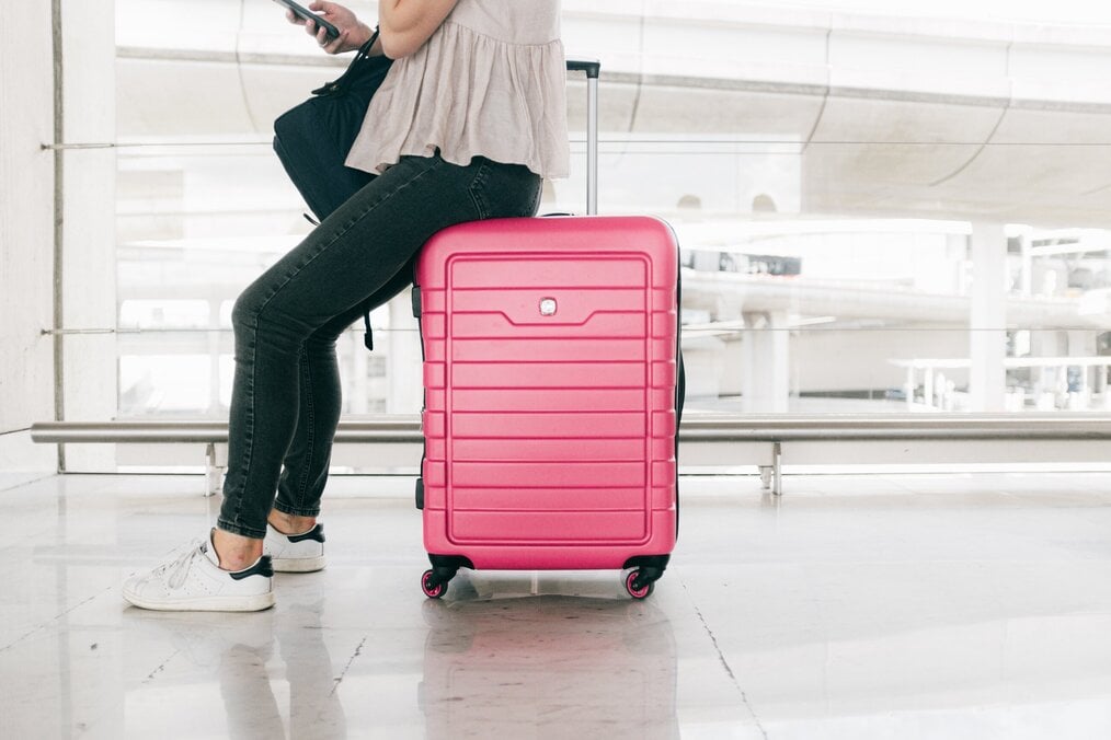 Person sitting on suitcase at airport