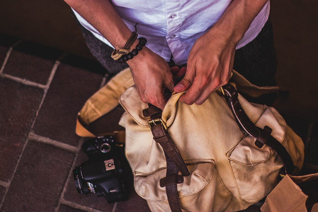 A person packing a tan backpack