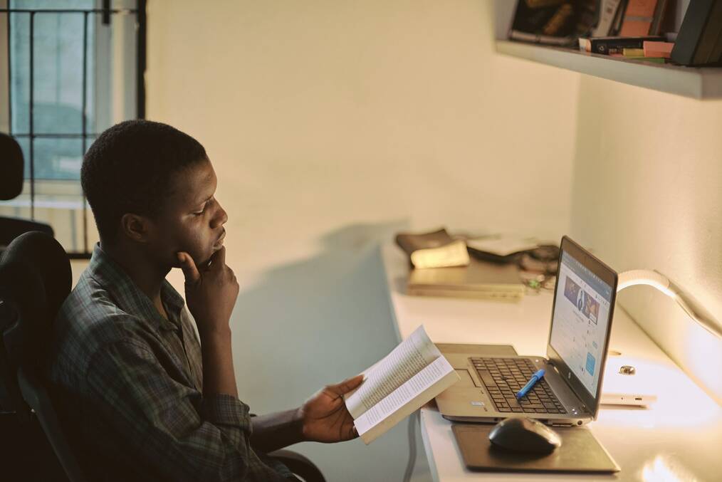 A man rests his chin on his hand as he looks at an open book.
