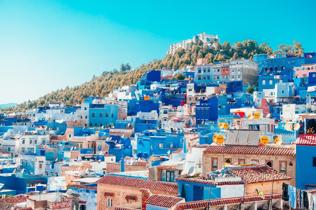 Bright blue houses line a steep hill in Morocco.