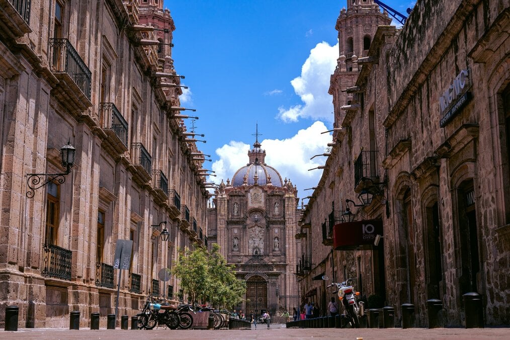 A street view of a cathedral in Mexico framed by a bright blue sky.