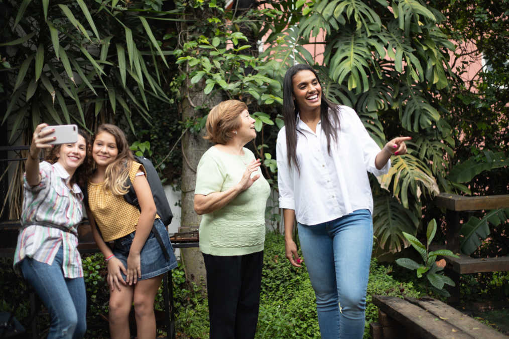 Three study abroad students with a host mom in a tropical backyard