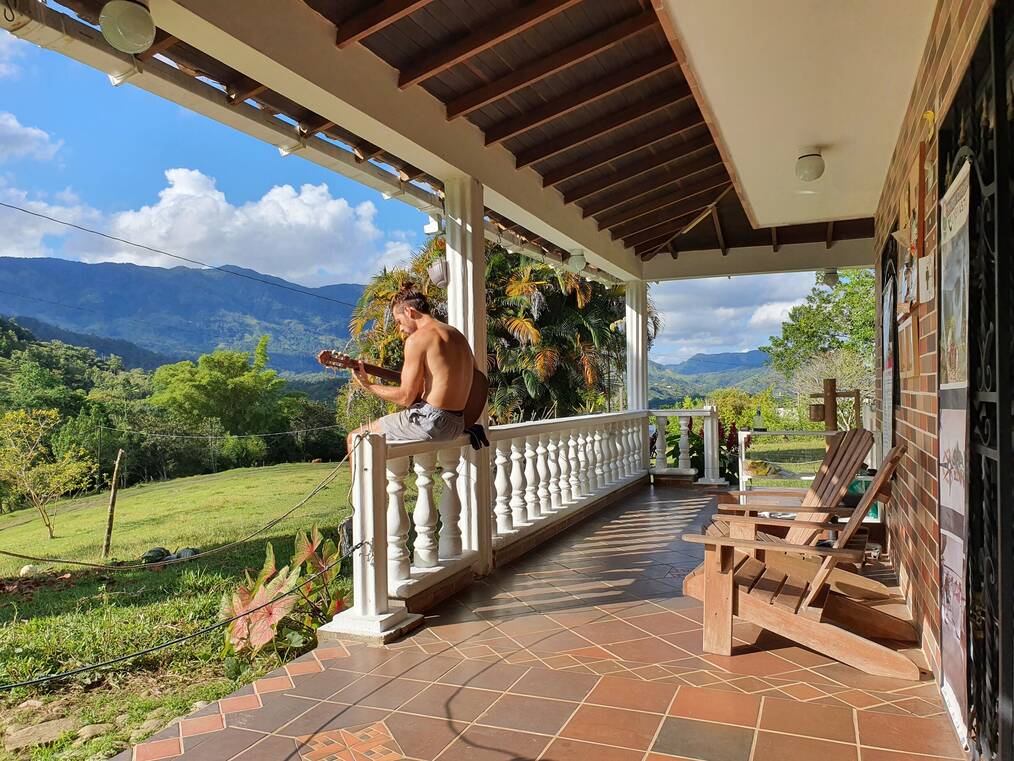 Traveler sitting on the porch of a home holding a guitar