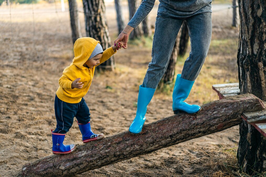 Photo by Oleksandr Pidvalnyi on Pexels An adult holds the hand of a child as they walk up a log.