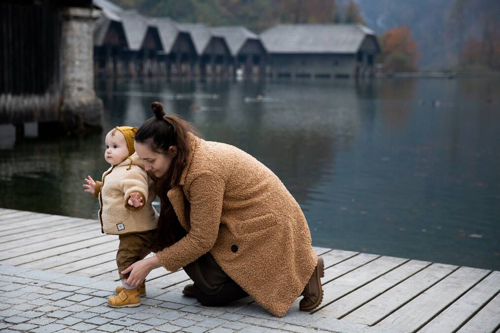 Woman in Brown Coat Kneeling on Brown Wooden Dock.