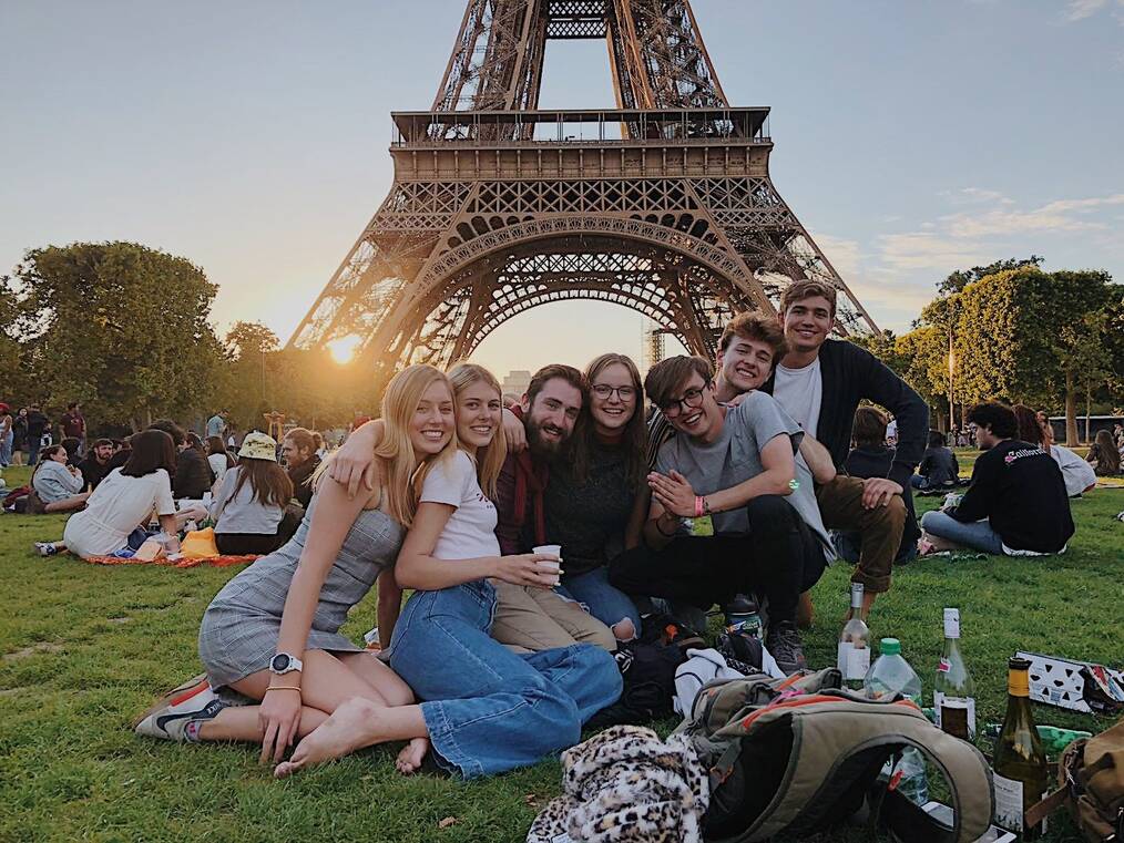 A group of students pose in front of the Eiffel Tower in Paris.