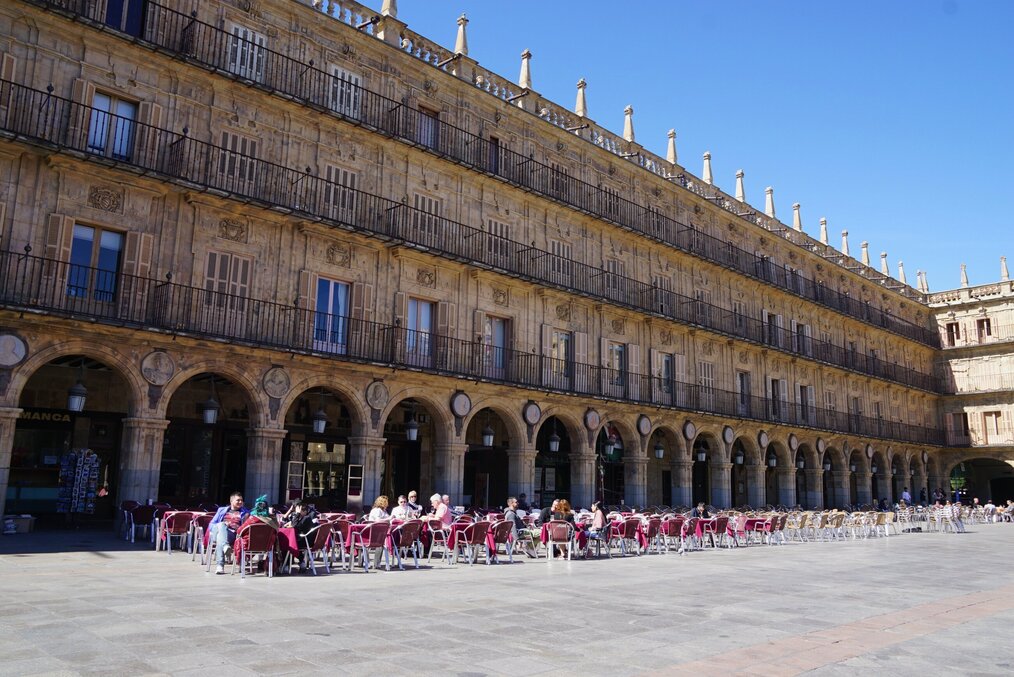 Photo by Beth Macdonald on Unsplash People sit at tables in the Plaza Mayor in Salamanca, Spain.