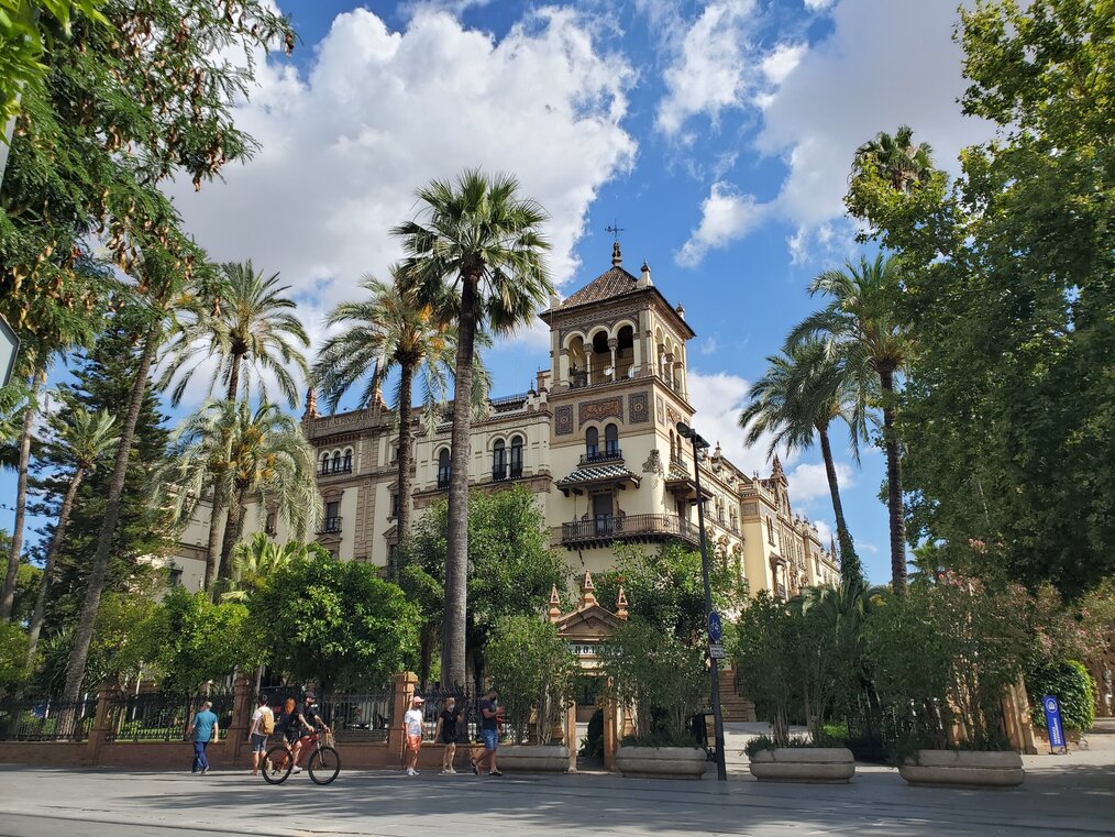 Photo by Hasmik Ghazaryan Olson on Unsplash Palm trees in front of a large building in Seville, Spain.