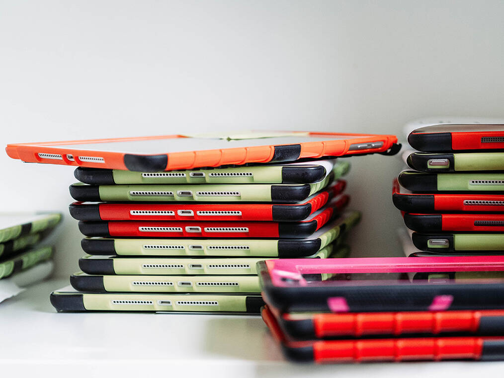 A stack of iPads with kid friendly cases on them