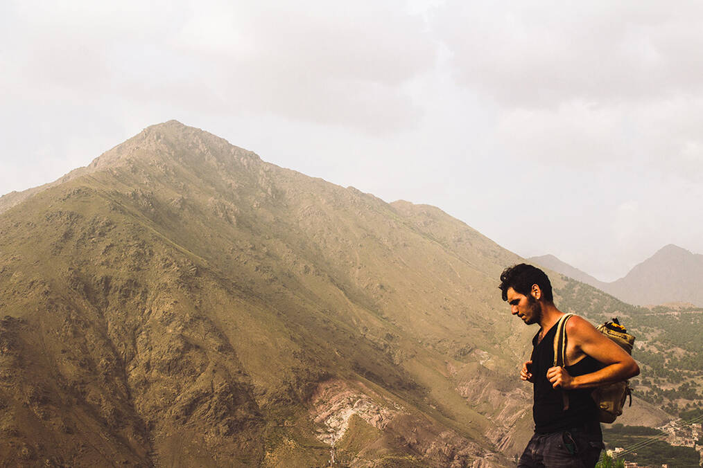 A man hiking with a tall peak in the background