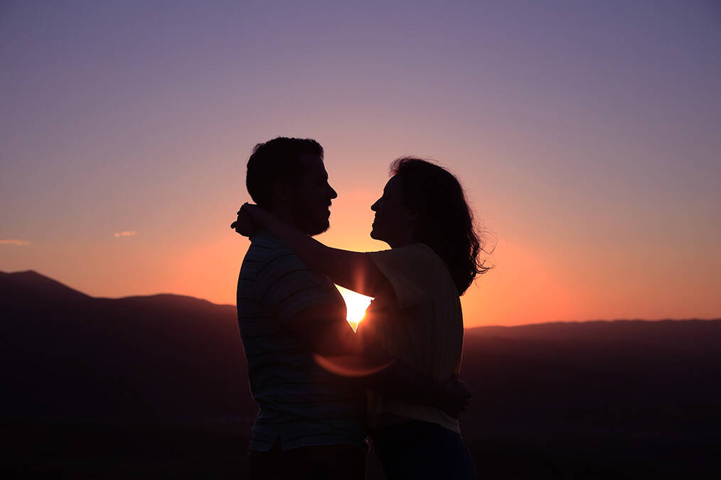 A couple hugging with a sunset in the background