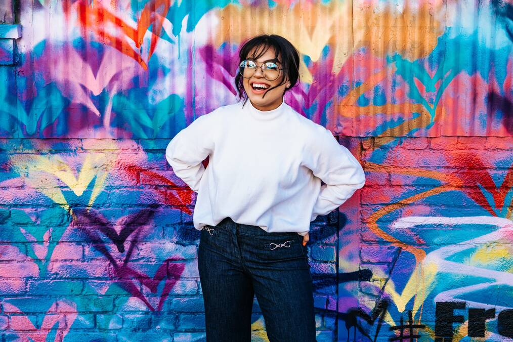 A study abroad student wearing a white long sleeve shirt and glasses smiling