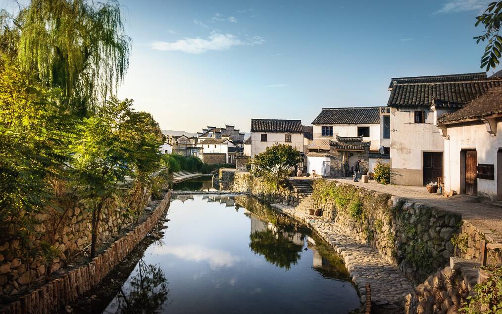 A river flows beside houses in a village in China.