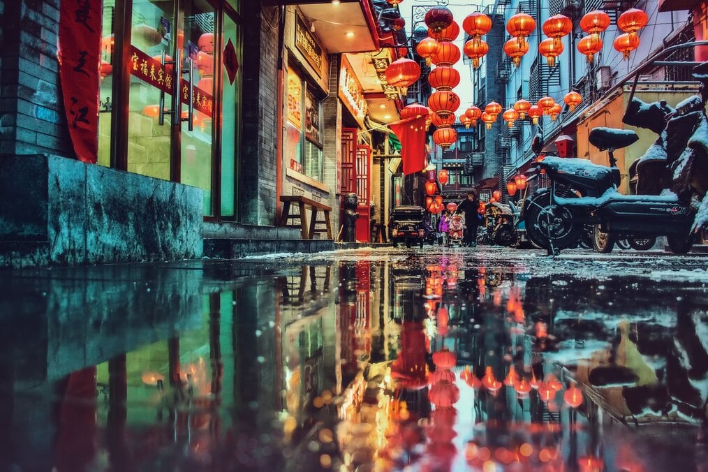 Photo by zhang kaiyv on Unsplash Neon signs reflect on puddle on street in China.