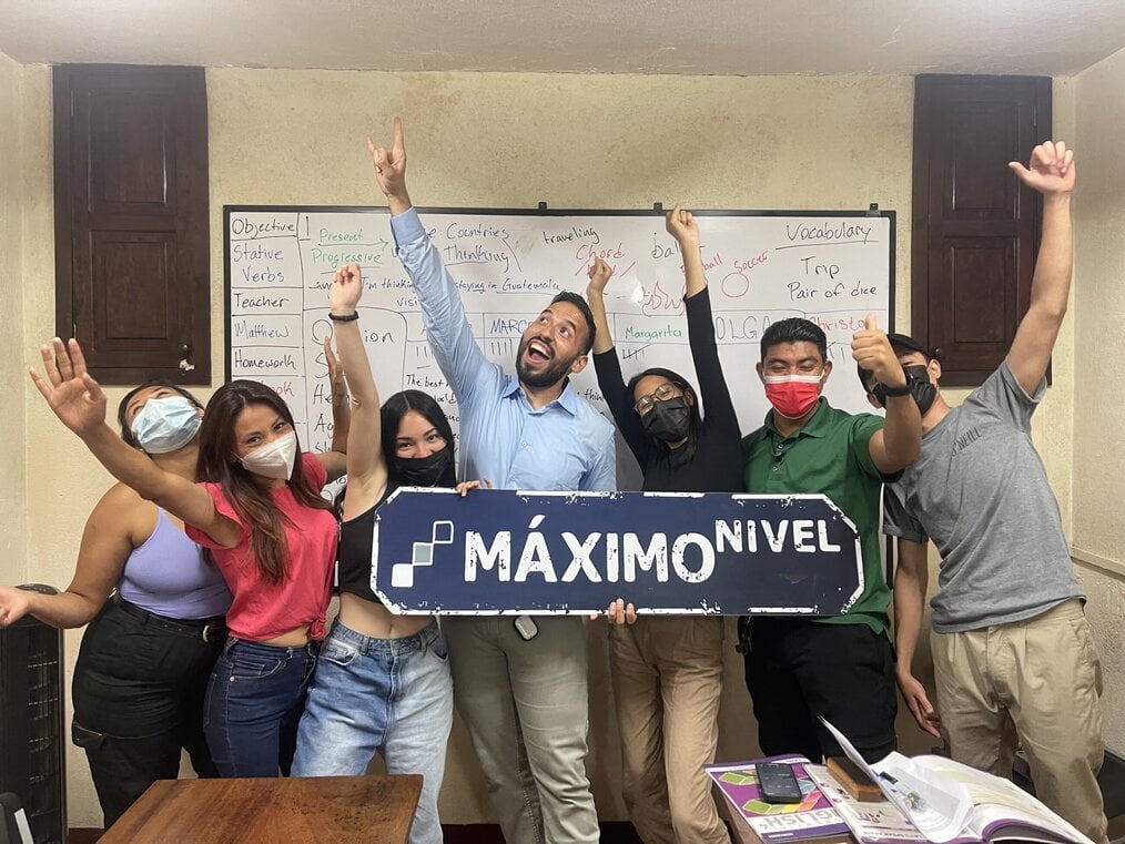TEFL Certification in Antigua, Guatemala, Matthew Macedo Several people wearing masks hold a sign and raise their fists in the air.