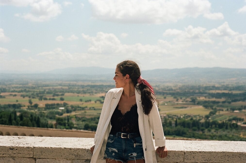 daniela-andrade-00AyRdBRuBU-unsplash A woman leans against a low wall and looks to the side.