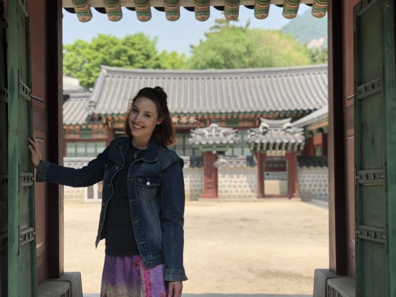 Korea A woman smiles and poses in a doorway.