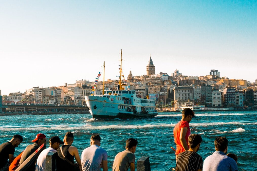 Photo by Meriç Dağlı on Unsplash Men sit along a pier at a harbor in Turkey.
