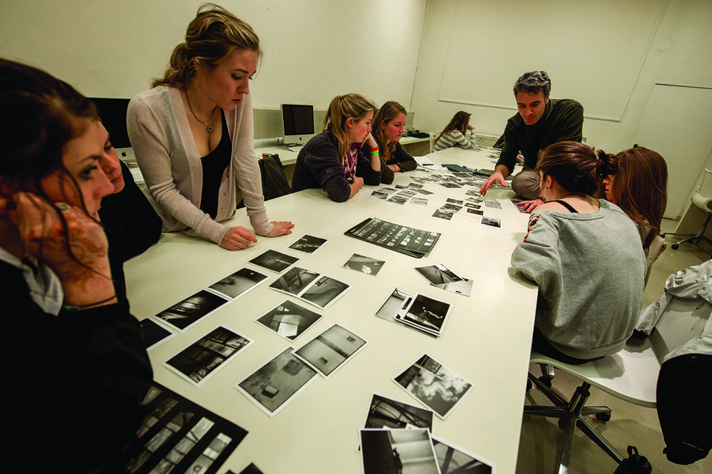 SAI Students sit around a table looking at black and white photographs.