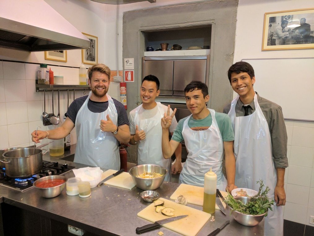 AIFS SA Four men in aprons pose in front of table with food ingredients on it.
