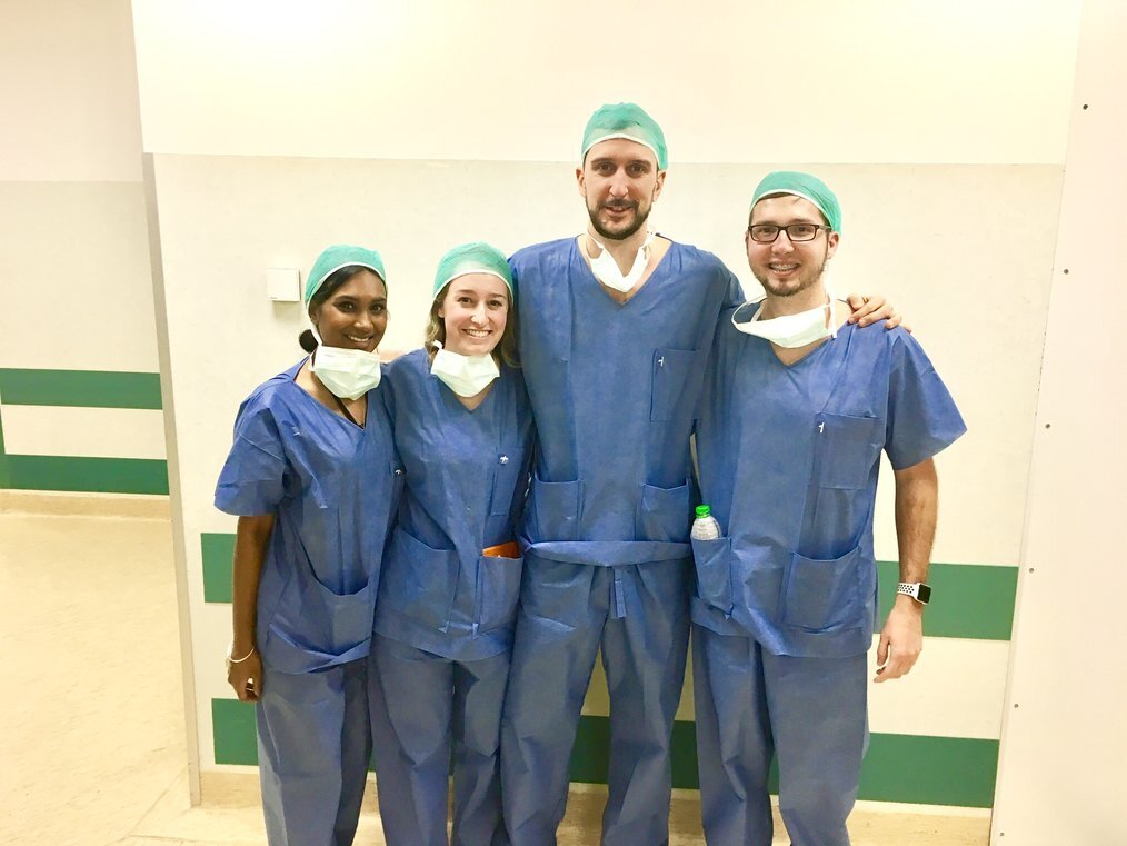 Atlantis Four students in blue surgical scrubs pose for the camera.