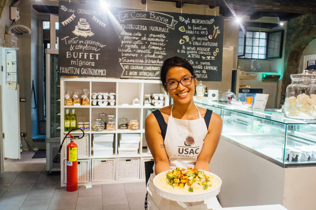 USAC A smiling woman holds a plate of food.