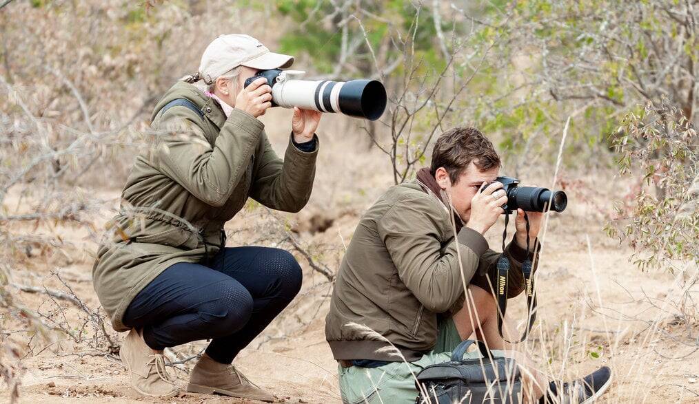 Two people crouch and take photos.